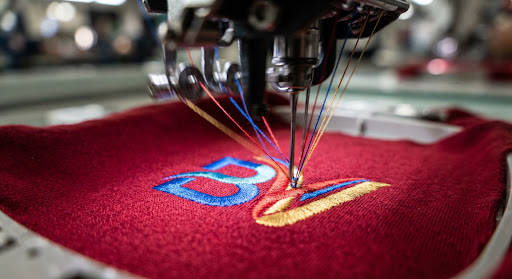 Embroidery needles stitching a logo onto red fabric