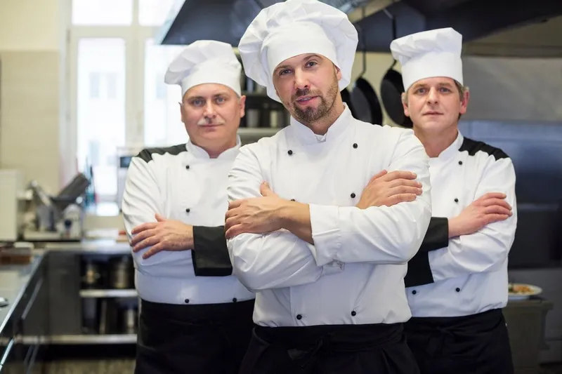 Three chefs in white chef jackets in a restaurant kitchen