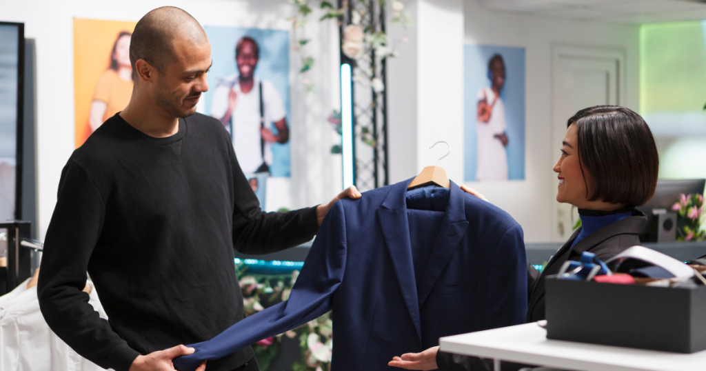 A customer and a stylist discussing a navy blue suit jacket as part of a custom clothing in Dubai.