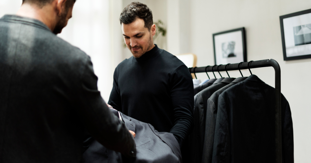 Man selecting custom clothing in Dubai with a variety of tailored suits on display.