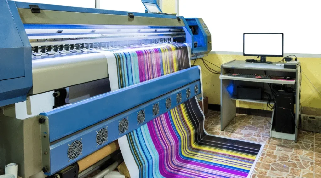 Large format digital printing equipment producing vibrant colorful banners and signage in professional print shop setting.
