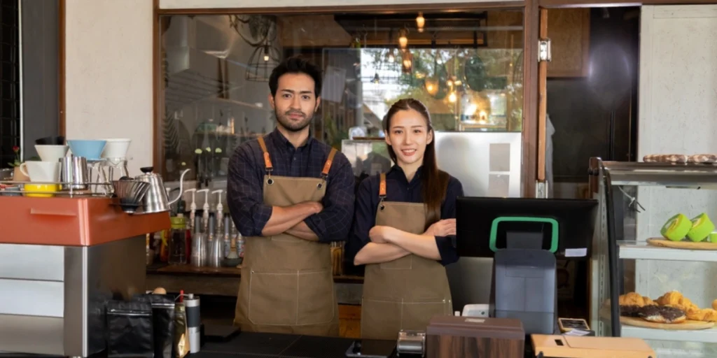 Café staff in aprons wearing café staff uniforms at a modern coffee bar, UAE team portrait, café staff uniforms UAE.